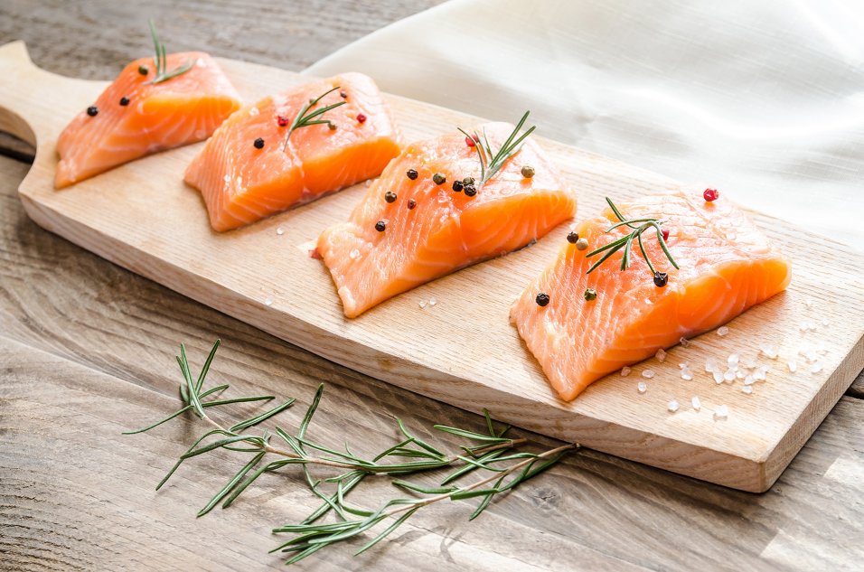 Salmon fillets on a wood platter with caper and salt garnish