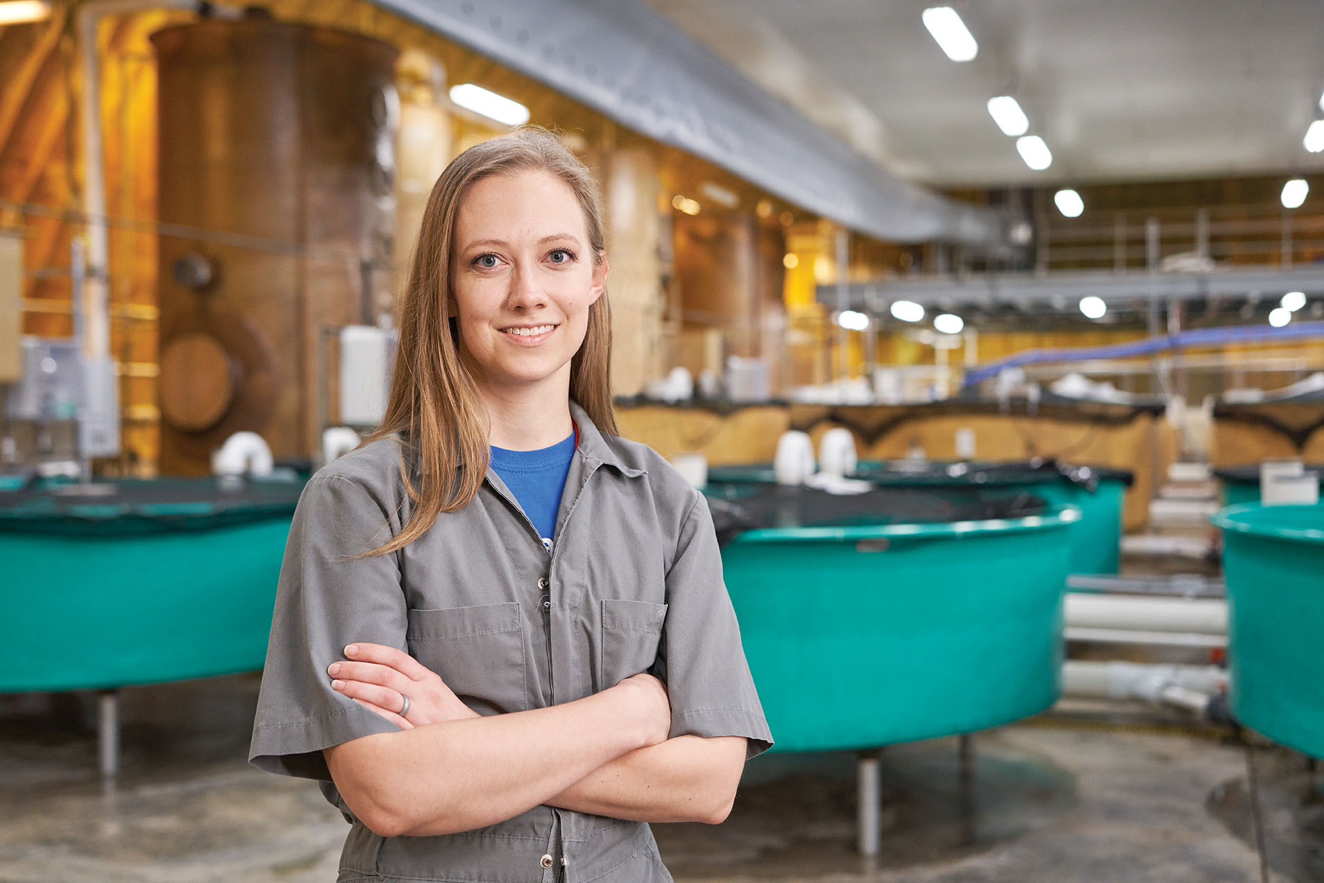 AquaBounty employee standing with arms folded in front of fish tanks