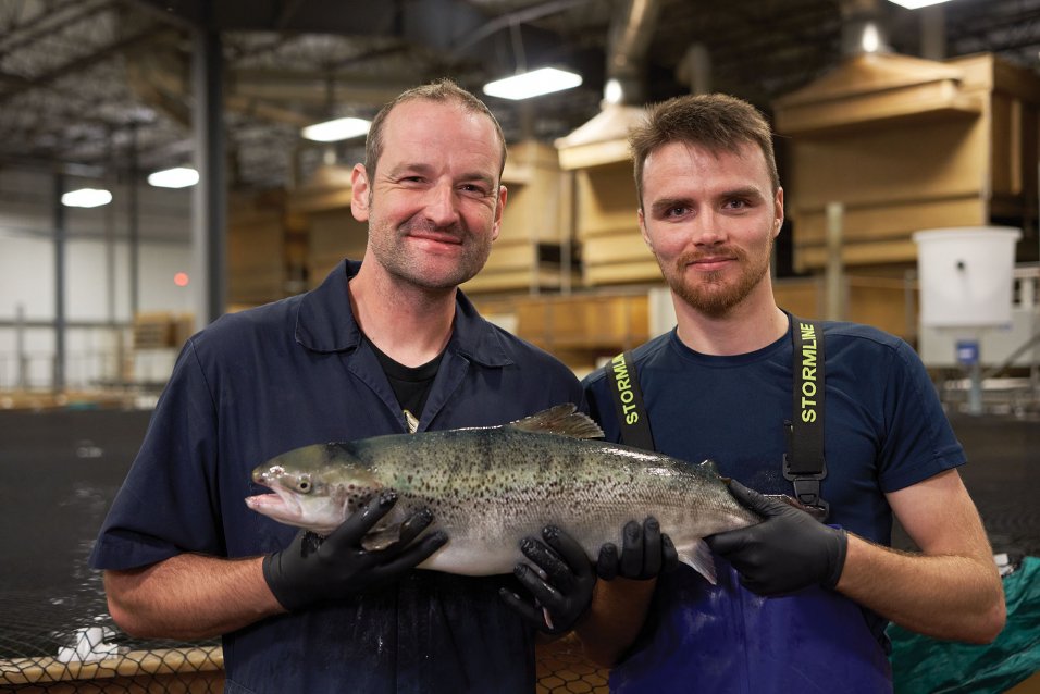 Two men smiling while holding a salmon