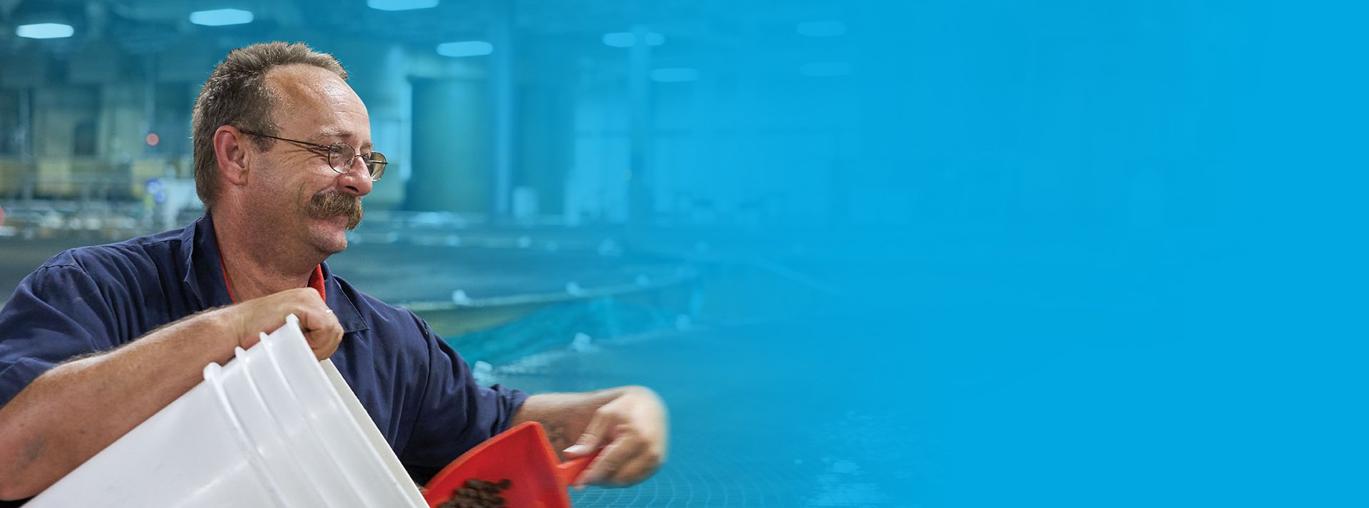 AquaBounty employee smiling and holding white buckets at the land-based fish farm 